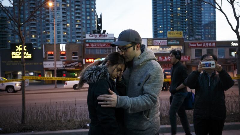 People embrace at the scene of a memorial for victims of a crash  in Toronto, Canada. Photograph: Cole Burston/Getty Images