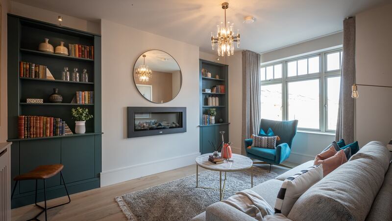 The ceiling heights at hall level are 2.6m and the living room has a large box bay window, a smart sage green uPVC design by Carlson and a Dimplex flame-effect electric fire.