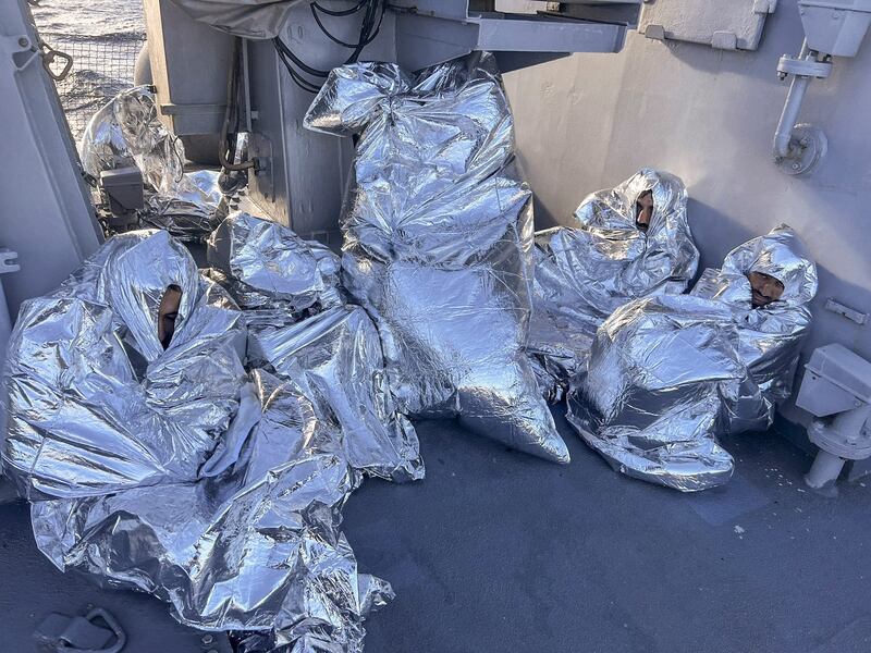 Some of the nine men who survived a shipwreck and were found on an uninhabited islet are covered with a thermal blankets as they sit aboard a Greek coastguard vessel in the Aegean Sea. Photograph: Greek coastguard/AP