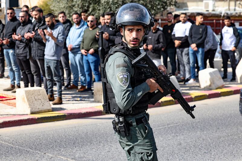 A member of the Israeli security forces walks past Palestinians performing the Friday noon prayer in occupied East Jerusalem. Photograph: Ahmad Gharabli/AFP via Getty Images