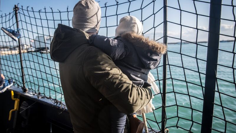 A father holds his baby on the deck of the Alan Kurdi, as the ship pulls into the port of Pozzallo, Italy, on December 29th, 2019. Photograph: Sally Hayden
