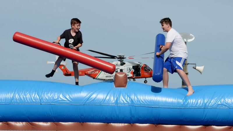 Children enjoy the amusements while the Coast Guard helicopter passes by during the Bray Air Display. Photograph: Alan Betson