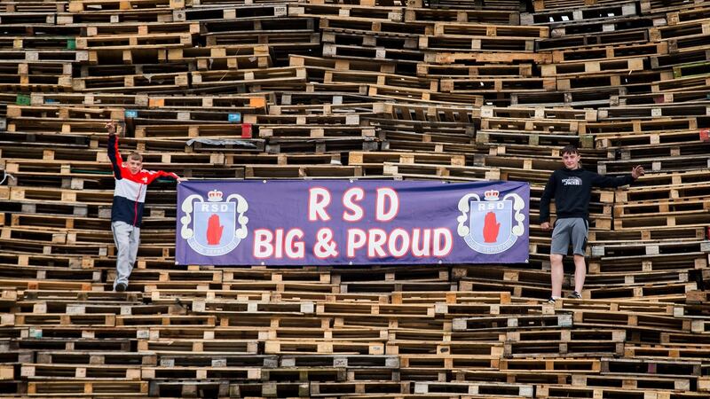 Two young boys pose for a photograph with a loyalist bonfire at Roden Street in Belfast. Photograph: PA Wire