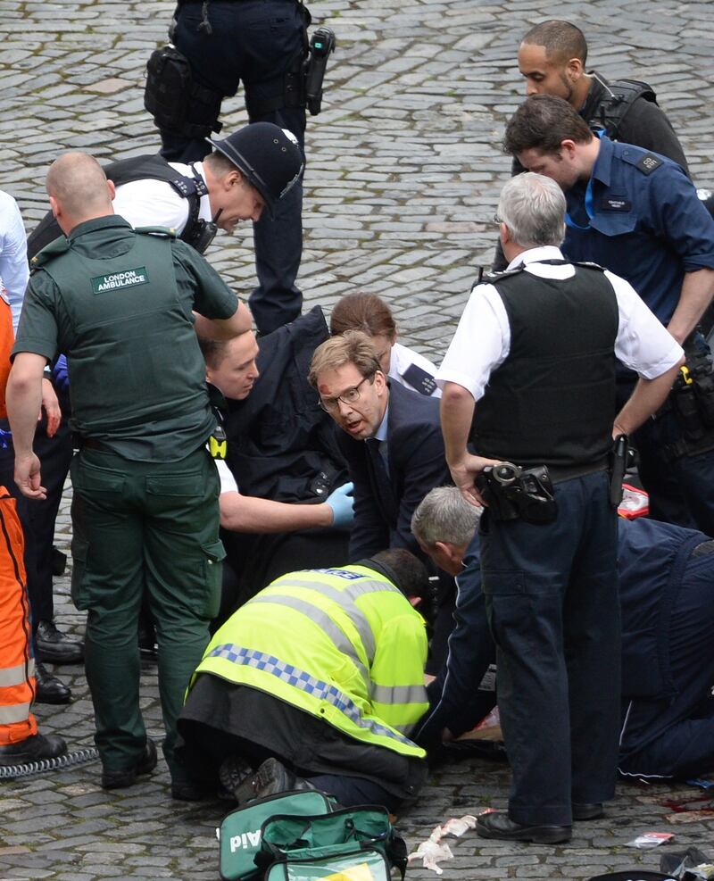 Conservative MP Tobias Ellwood (centre) helps emergency services attend to a police officer outside the Palace of Westminster, London. Photograph: Stefan Rousseau/PA Wire
