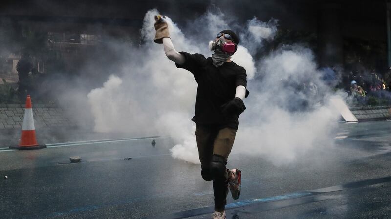 A protester wearing a gas mask throws back a tear gas after police fired tear gas during an anti-government rally in Hong Kong. Photograph: EPA