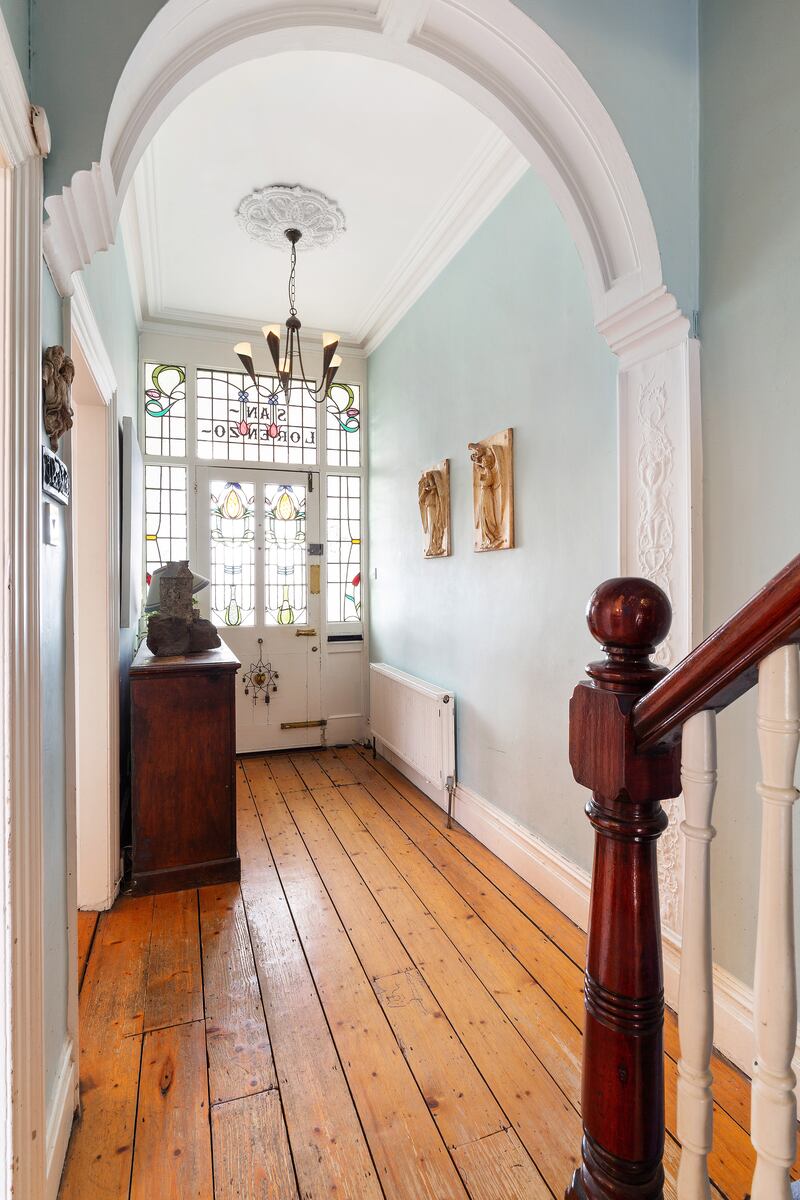Hallway with arch and stained-glass front door.