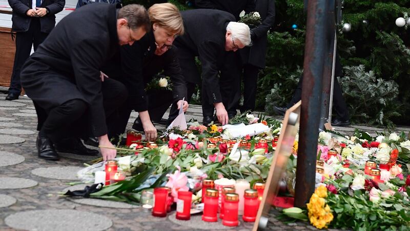 German chancellor Angela Merkel  with Berlin’s mayor Michael Mueller  and German interior minister Thomas de Maiziere lay down flowers at a makeshift memorial for the victims of an attack in Berlin. Photograph: Tobias Schwarz/AFP/Getty
