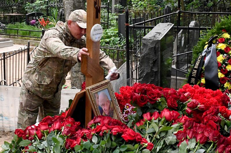 A man wearing camouflage places an angel figurine at the grave of Wagner private mercenary group chief Yevgeny Prigozhin. Photograph: Olga Maltseva/AFP via Getty