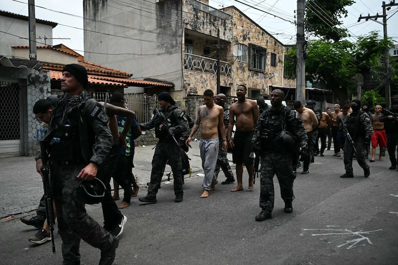 Police officers escort alleged criminals arrested during operation at the Vila Cruzeiro favela on Tuesday. Photograph: Mauro Pimentel/AFP via Getty