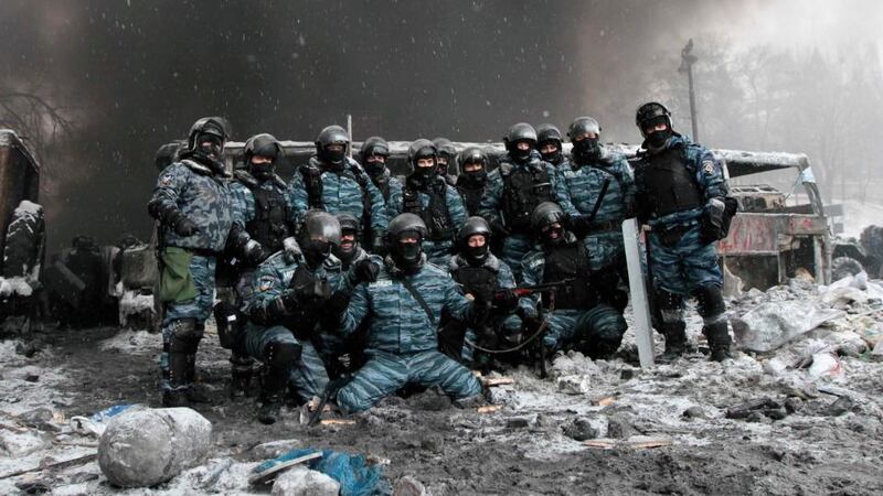 Riot police officers pose for a picture near burnt vehicles as smoke rises in the background during clashes with pro-European protesters in Kiev. Photograph: Reuters.