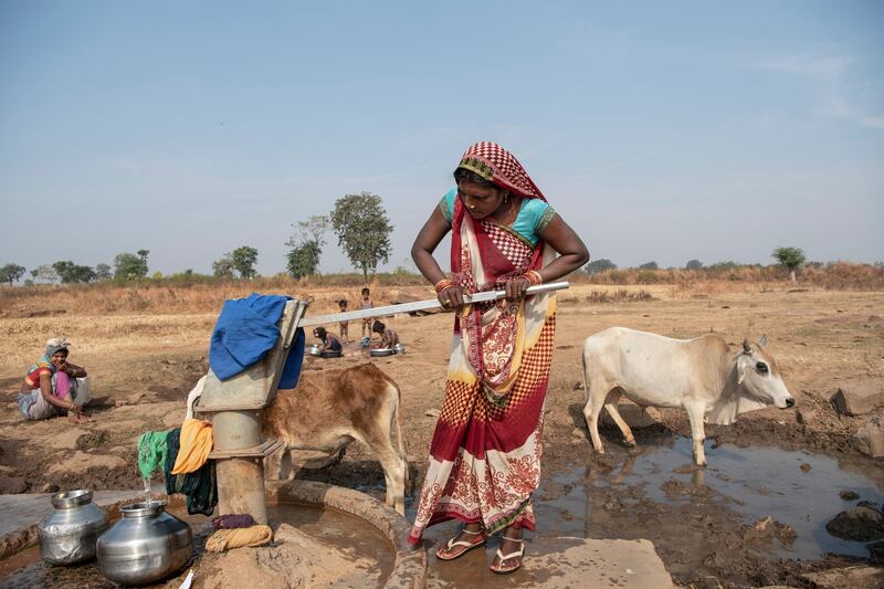 Bhoori Bai Ggound fills water containers with a hand pump well in Imlidol, India on November 30th, 2021. Photograph: Saumya Khandelwal/The New York Times