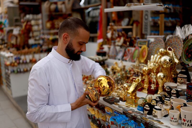 A shopkeeper arranges his football merchandise outside his store in a market area in Doha ahead of the World Cup which will bring thousands of foreign football fans to the city. Photograph: Odd Andersen/AFP via Getty Images