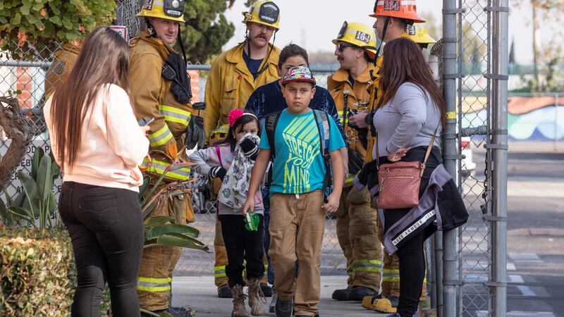 Students leave Cudahy Elementary School with their parents as they are evacuated after an  aircraft dumped fuel over the school in Los Angeles on Tuesday. Photograph: Etienne Laurent/EPA