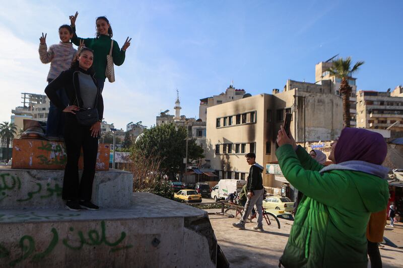 Syrians pose for pictures at the site where a statue of late Syrian president Hafez al-Assad was destroyed, in the coastal city of Latakia. Photograph: Aaref Watad/AFP via Getty Images
