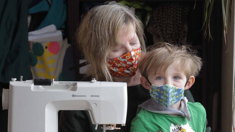 Textile printer Liz Walsh with her 3-year-old son Tadhg Jackson. Ms Walsh has been making protective masks at home in Dublin and plans to give them to family, friends and people working in shops and hospitals. Photograph: Mark Stedman