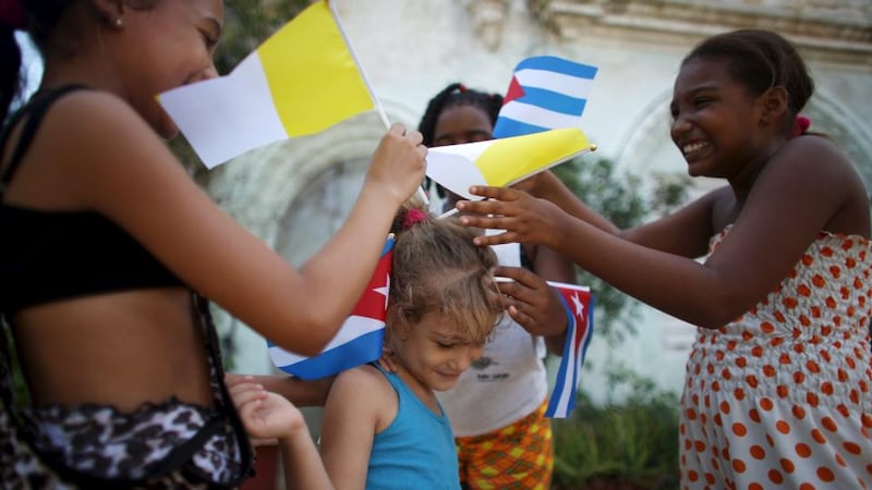Children adorn the hair of Ana Karla, 5, with Cuban and Vatican flags as they wait for the arrival of Pope Francis from the airport in Havana. Photograph: Alexandre Meneghini/Reuters