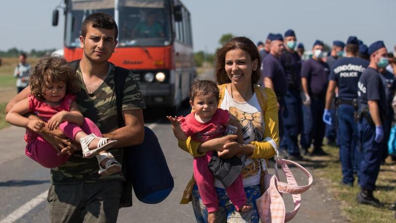 A migrant family who have just crossed the border from Serbia into Hungary walk towards buses organised by the police that will take them to a nearby reception centre  close to the village of Roszke, on Friday. Photograph:  Matt Cardy/Getty Images