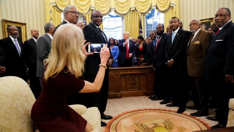 Kellyanne Conway kneeling on a couch in the Oval Office as she takes a picture of US president Donald Trump with members of the historically black colleges and universities. Photograph: Aude Guerrucci/EPA