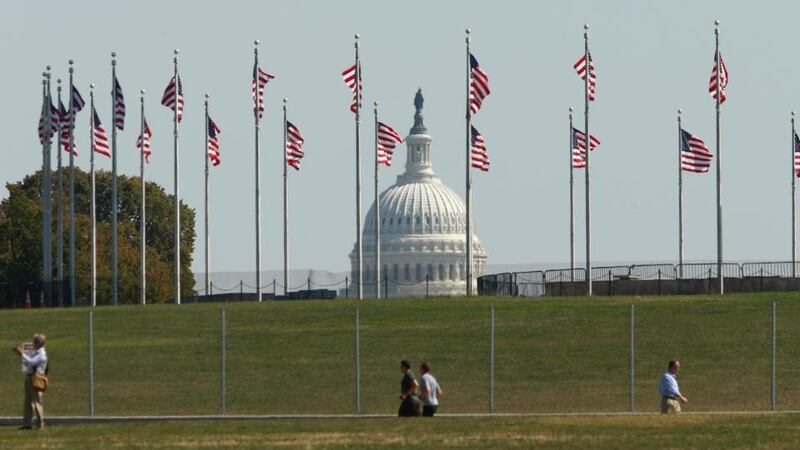 The dome of the US Capitol is seen though American Flags in Washington. Up to one million federal workers were thrown temporarily out of work today as the US government partially shut down for the first time in 17 years in a standoff between President Barack Obama and congressional Republicans over healthcare reforms. Photograph: Kevin Lamarque/Reuters