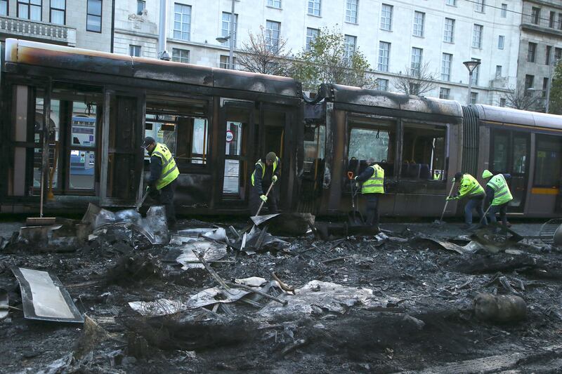 Workers clear debris from a burned-out Luas on Dublin's O'Connell Street this morning. Photograph: Stephen Collins/Collins Photos
