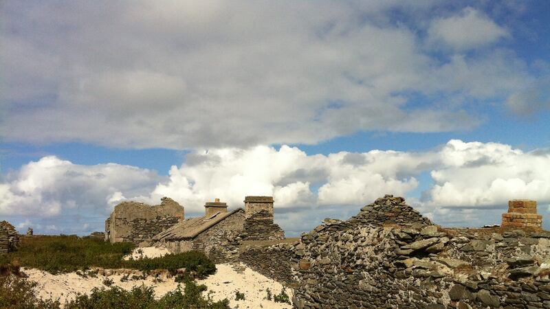 Ruined village houses standing in a semi-circle on a white sand beach on South Iniskea
