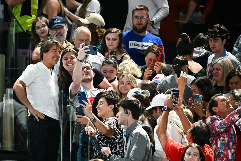 US actor Tom Cruise takes selfies with fans as he attends the artistic gymnastics women's qualification at the Bercy Arena in Paris. Photograph: Loic Venance/AFP via Getty Images