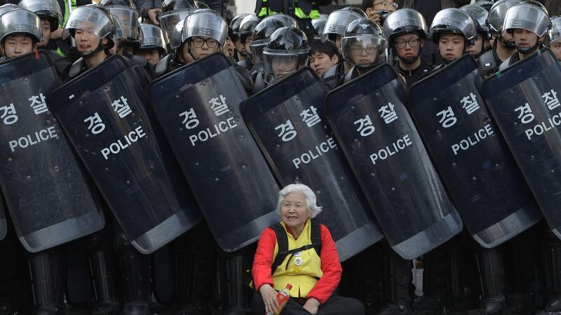 A woman sits in front of riot police during an anti-government protest in Seoul in April 2015. Photograph: Chung Sung-Jun/Getty Images