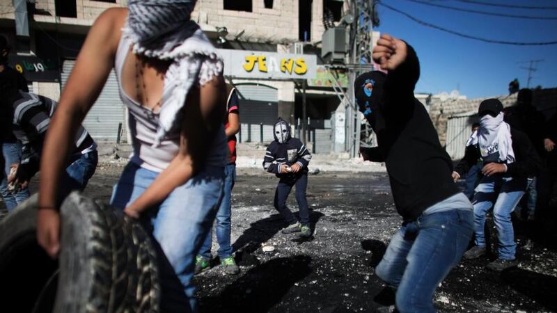 Palestinian youths throw stones towards Israeli border police during clashes at a checkpoint between the Shuafat refugee camp and Jerusalem today. Photograph:  Finbarr O’Reilly/Reuters.