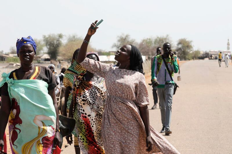 A South Sudanese returnee, who fled Khartoum, trying to find a phone signal after arriving from Sudan, at the border town of Wunthaou, South Sudan. Photograph: Amel Pain/EPA-EFE