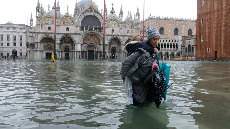 A woman with a child walks in the flooded St Mark’s Square  in Venice. Photograph:  Manuel Silvestri/Reuters