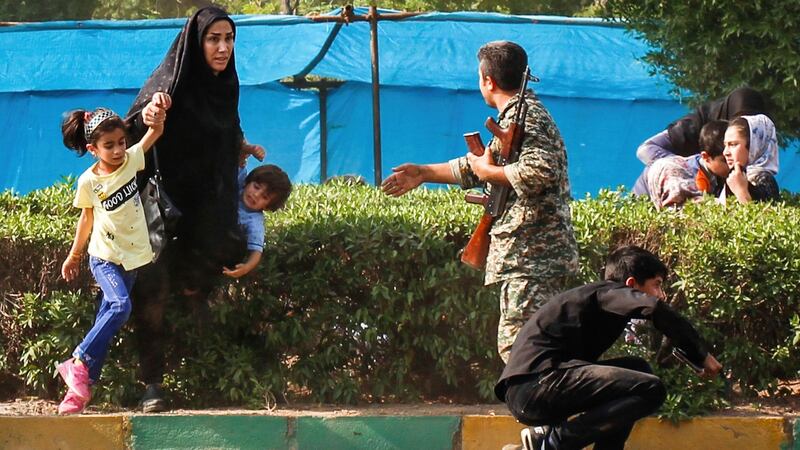 A woman takes her children to shelter as an army member tries to help them, during the shooting. Photograph: Fatemeh Rahimavian/AP