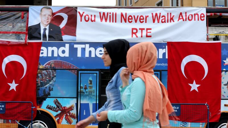 People pass in front of a tourist bus with Turkish flags and placards with a picture of Turkish president Recep Tayyip Erdogan, in Istanbul. Photograph: Tolga Bozoglu/EPA