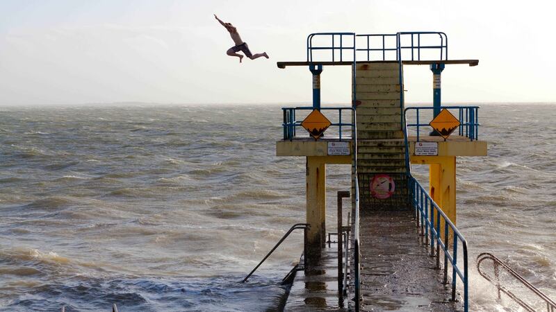 A teenager jumps off the diving platform at Salthill as storm ‘Henry’ approaches. Photograph: Andy Newman.