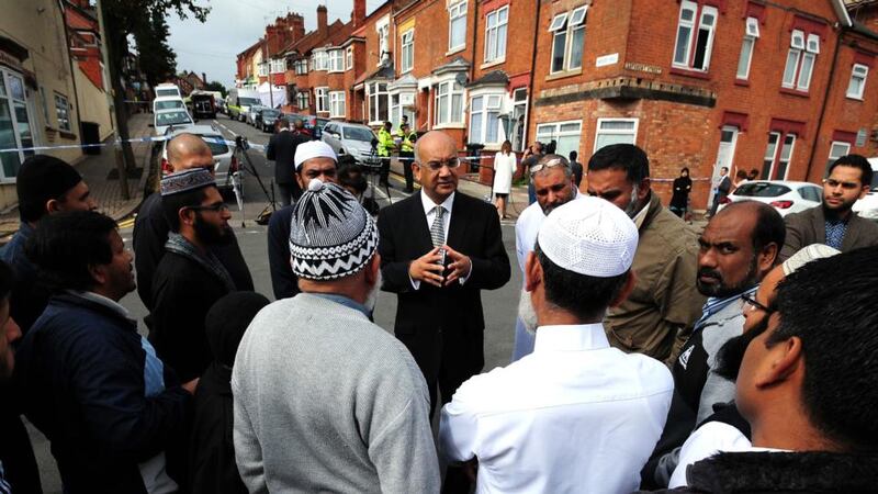 British  MP Keith Vaz (centre) meets residents yesterday near  the scene of a house fire (in background) at Wood Hill, in the Spinney Hills area of Leicester, which claimed the lives of Shehnila Taufiq and her three children. Photograph: Rui Vieira/PA Wire