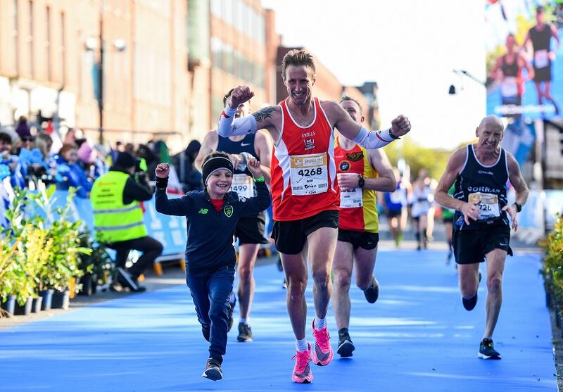 Alvin Duggan crosses the finish-line with Donnacha Maher, aged 6, from Enniscorthy, Co Wexford, during the 2019 Dublin Marathon. Photograph: Sam Barnes/Sportsfile