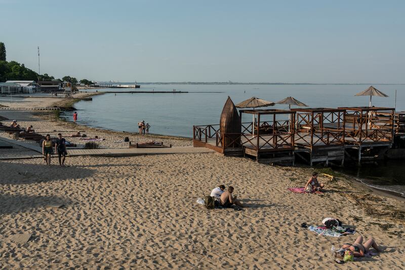People visit Otrada Beach, where items from communities along the Dnieper River have been washing up after the destruction of the Kakhovka dam in Odesa. Photograph: Brendan Hoffman/The New York Times
                      