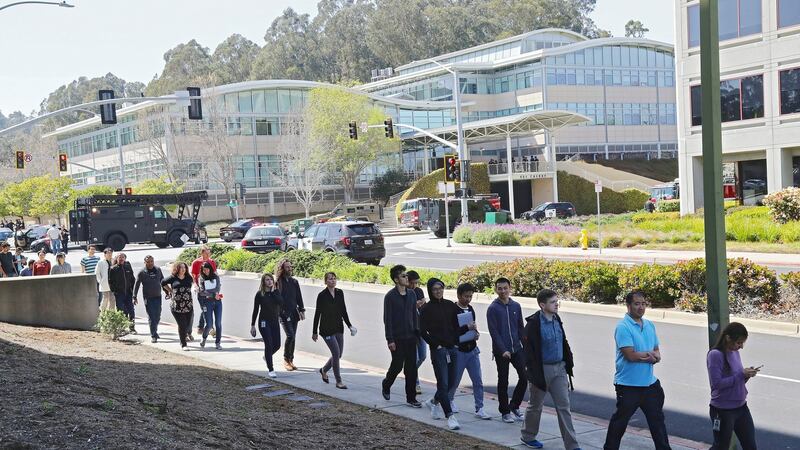 YouTube employees walk away from their place of work, in background, after a shooting incident, in San Bruno, California. PhotographL: Jim Wilson/The New York Times