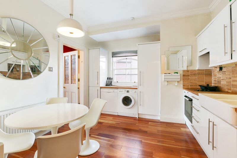 The kitchen is to the right of the livingroom; it is compact with room for a small dining table. It has modern-looking white gloss units and a double sink.