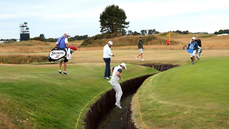 Rory McIlroy jumps into the Barry Burn to get his golf ball during a practice round. Photo: Jason Cairnduff/Reuters