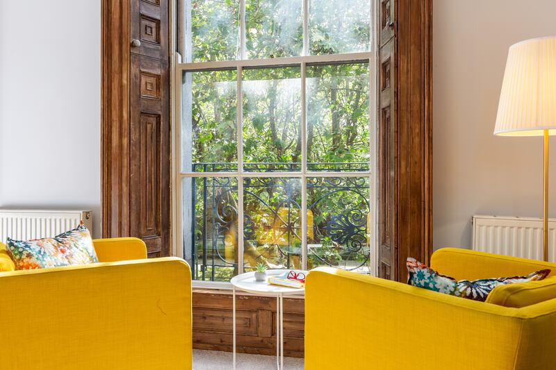Armchairs by the sash window in the main bedroom of the second unit