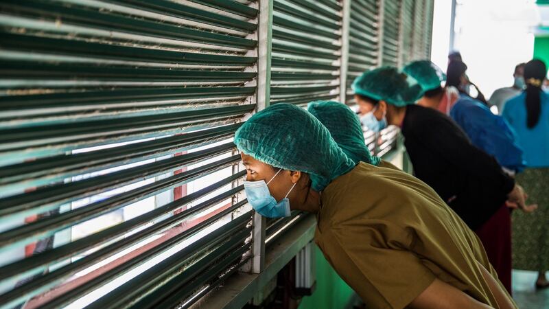 Healthcare workers in Yangon watch protesters demonstrate against Myanmar’s military coup. Photograph: The New York Times