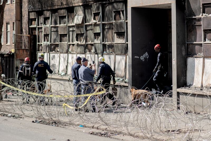 A South African Police Service canine unit leaves the burned apartment block in Johannesburg. Photograph: Luca Sola/AFP