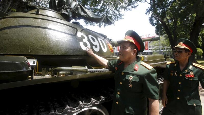 Tank 390’s first gunner Ngo Sy Nguyen (left) and second gunner Le Van Phuong stand next to their tank, which was operated by North Vietnamese forces and crashed through the gates of the Reunification Palace, formerly the Presidential Palace, 40 years ago.  Photograph: Kham/Reuters