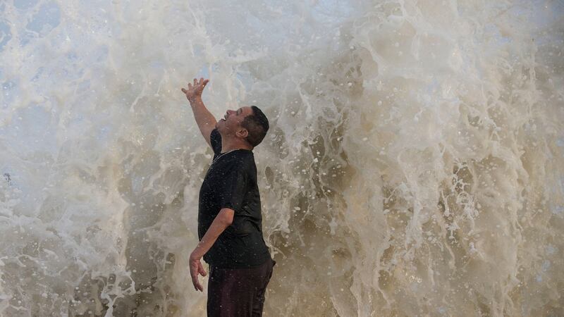 Water falls over Jimmy Villarreal, of Galveston, Texas as a wave hits the seawall while he was watching the surf stirred up by Hurricane Laura Wednesday, Aug. 26, 2020 in Galveston, Texas. (Brett Coomer/Houston Chronicle via AP)