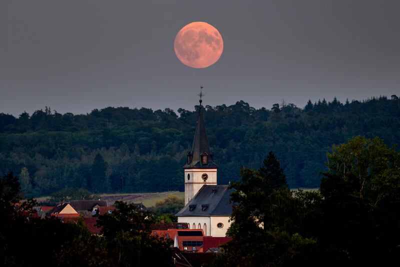 Germany: The harvest supermoon rises behind the church in Wehrheim near Frankfurt. Photograph: Michael Probst/AP