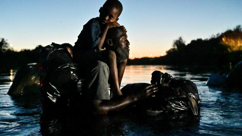 A man carries a child on his shoulders as Haitian migrants cross the Rio Grande. Photograph: Pedro Pardo/AFP via Getty Images