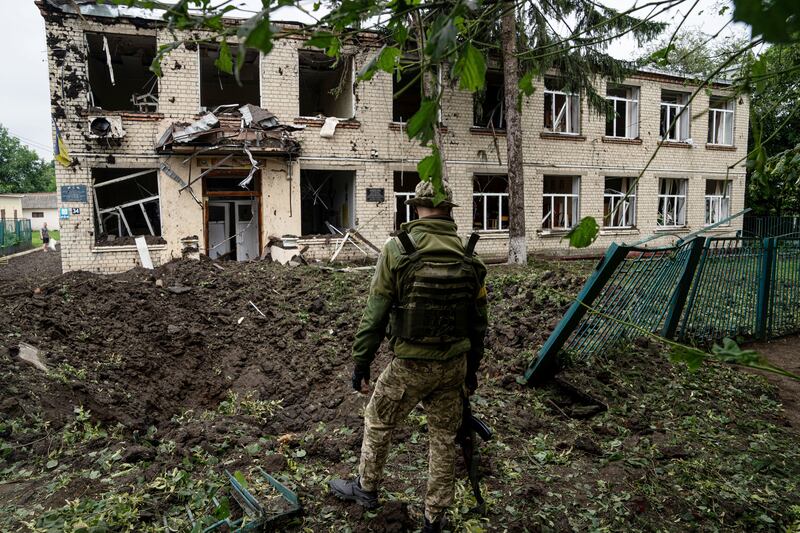 A Ukrainian serviceman looks at a damaged school after Russian shelling in Chuhuiv, Kharkiv region. Photograph: AP
