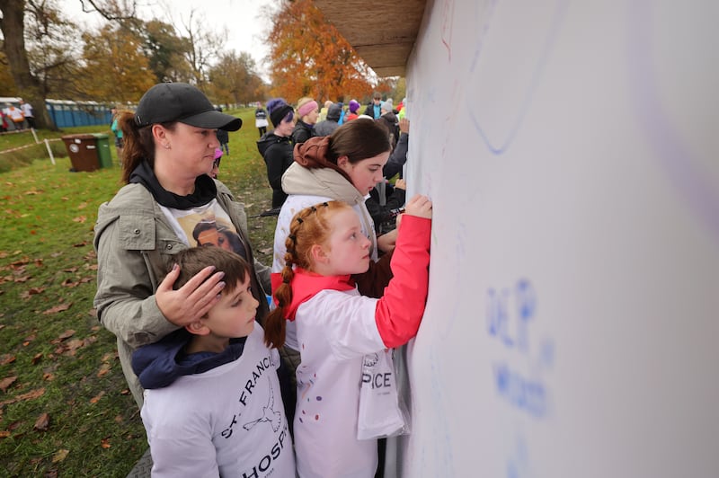 Noah Kinsella (foreground) and his sister Lacey Kinsella (background), with their aunt, Joanne O’Donnell (left) and cousin Millie O’Donnell, write a message on the Remembrance wall to their deceased mother/sister/aunt Maria Kinsella. Photograph: Alan Betson
