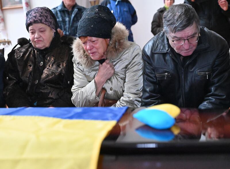 Olena Ignatenko, mother of Ukrainian children's writer Volodymyr Vakulenko, and close relatives mourn next to the coffin during a funeral ceremony at the St Demetrius Church in Kharkiv in December 2022. Photograph: Sergey Bobok/Getty Images