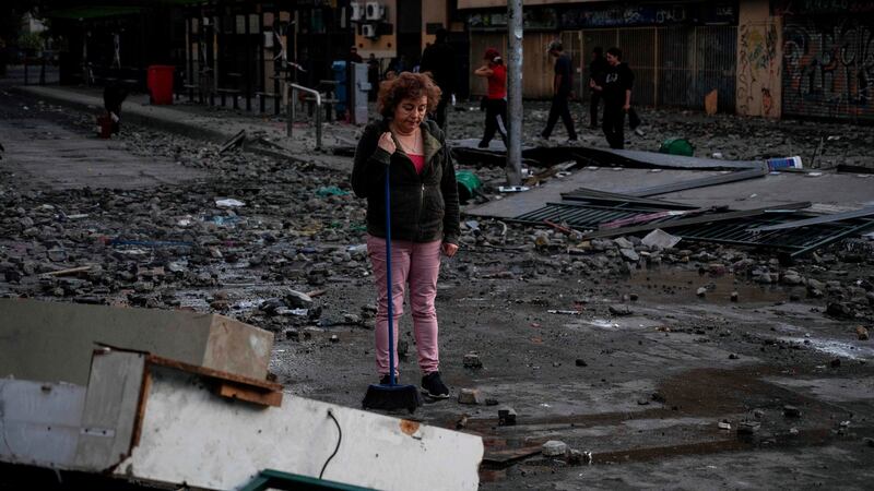 A  woman looks at a damaged street after clashes in Santiago on Monday. Photograph:  Pedro Ugarte/ AFP/ Getty